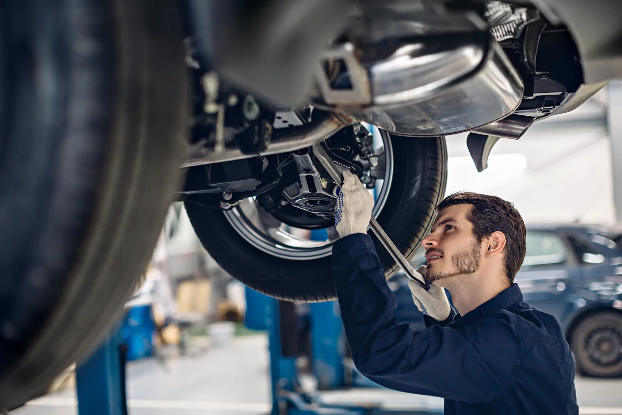 centre service reparation automobile mecanicien examinant suspension voiture